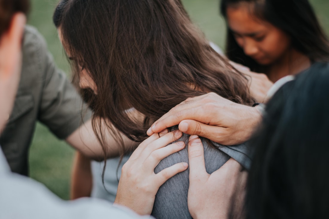 A group praying with hands on one another's shoulders