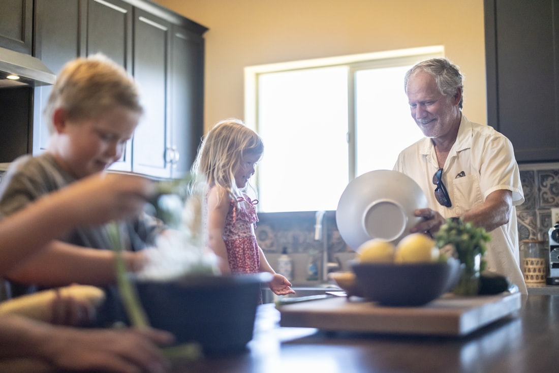 A grandfather and his grandchildren cooking together at home